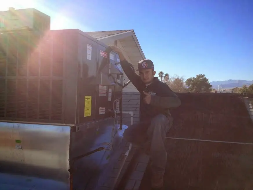 HVAC technician performing Air Duct Cleaning on a rooftop unit in Timonium